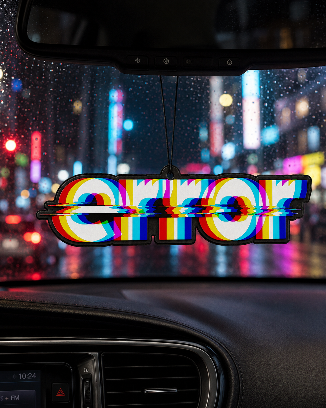 A novelty car air freshener spelling 'ERROR' with a glitch effect, hanging in a car windshield with a blurred city street scene in the background.